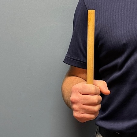 With elbow bent at your side, turn your forearm so the stick points to the ceiling.